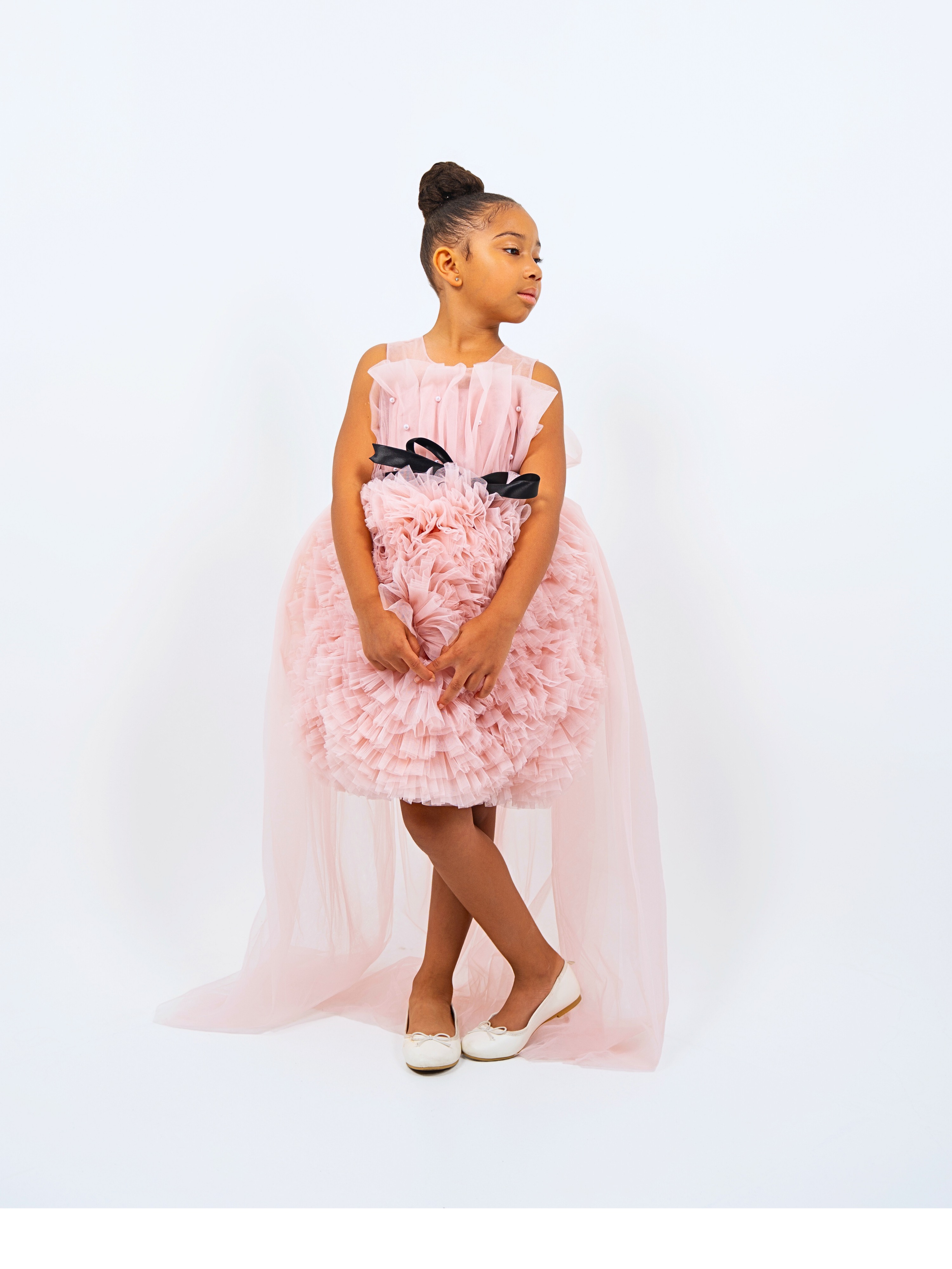 Girl in pink ruffle tulle high-low dress with black bow, styled for birthday, wedding or special event
